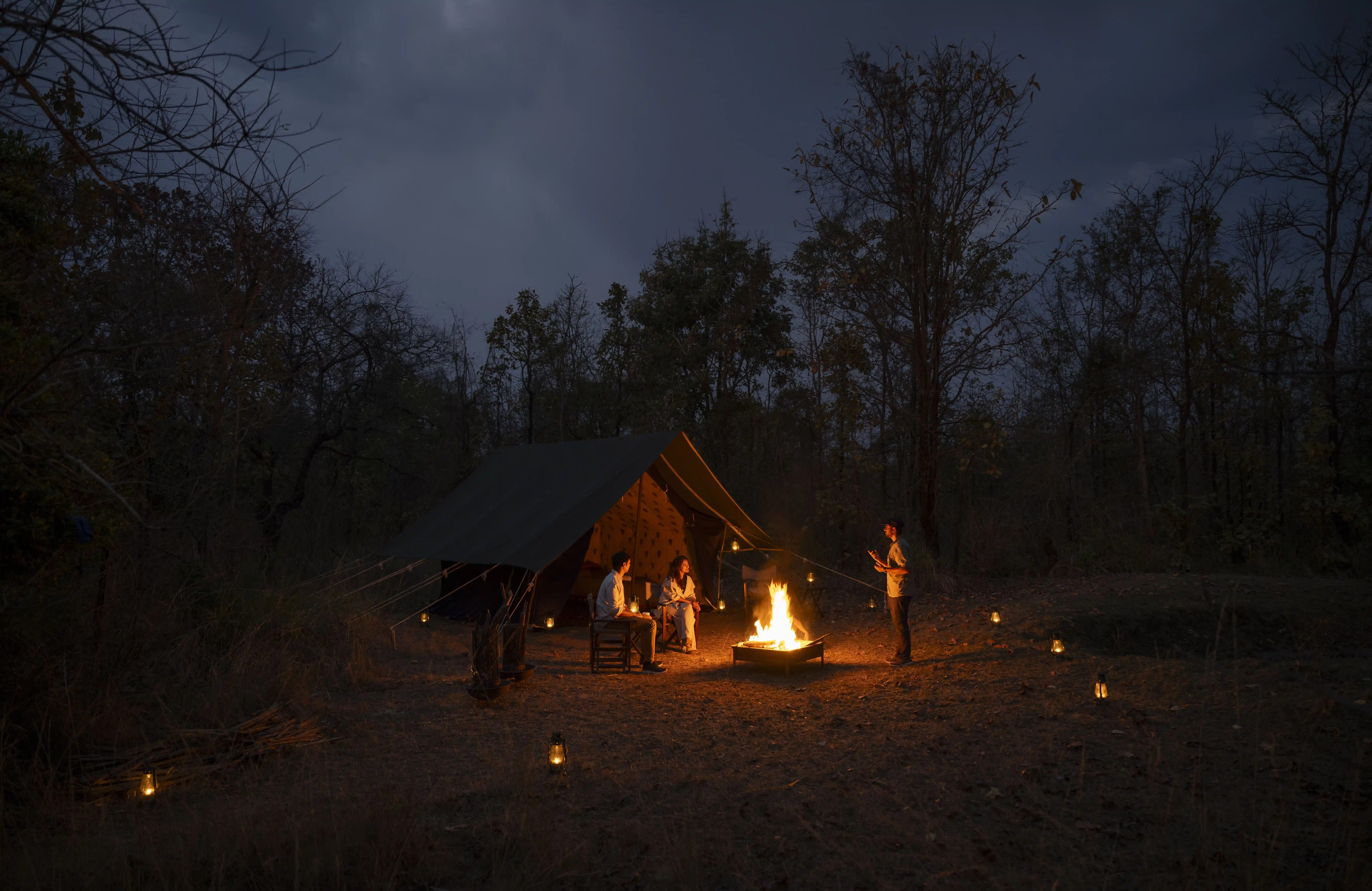 Night campfire beside a forest tent